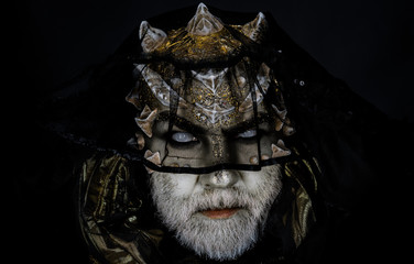 Alien, demon, sorcerer makeup. Demon on black background, close up. Dark arts concept. Senior man with white beard dressed like monster. Man with thorns or warts in black veil.