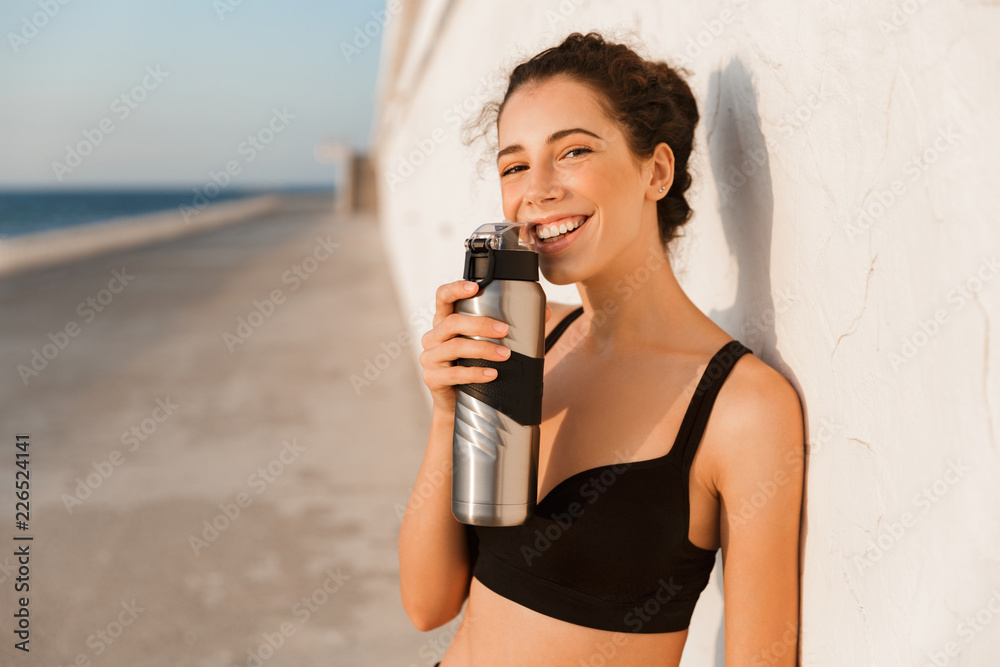 Sticker Smiling young sportswoman standing outdoors