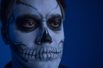 Portrait of a young man with a skull makeup for Halloween on a black background