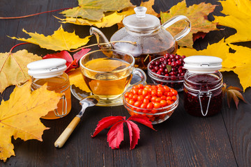 Tea of sea-buckthorn berries with honey on wooden table in fall enveronment