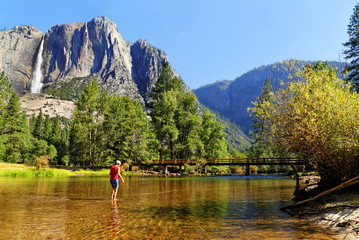 Frau im Merced River im Yosemite Valley mit Yosemite Fall, Kalifornien, USA