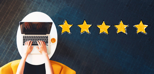 Five Star Rating with person using a laptop on a white table - obrazy, fototapety, plakaty