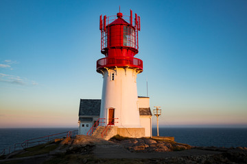 Old Lighthouse Lindesnes fyr is a coastal lighthouse located on the southernmost point of continental Norway in Lindesnes, South Cape. Serene Scandinavian landscape, Rocky Mountains, fjord, sunset sky - obrazy, fototapety, plakaty