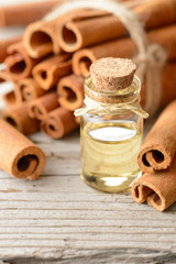 cinnamon essential oil in the glass bottle, with cinnamon sticks, on the wooden board