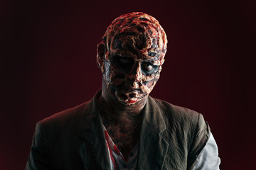 scary halloween theme and halloween makeup: scary man with a burnt face holds a baseball bat in his hands, serial maniac in a ragged suit, evil or angry superhero on a black background