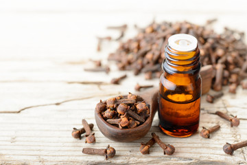 clove essential oil in the glass bottle, on the wooden board