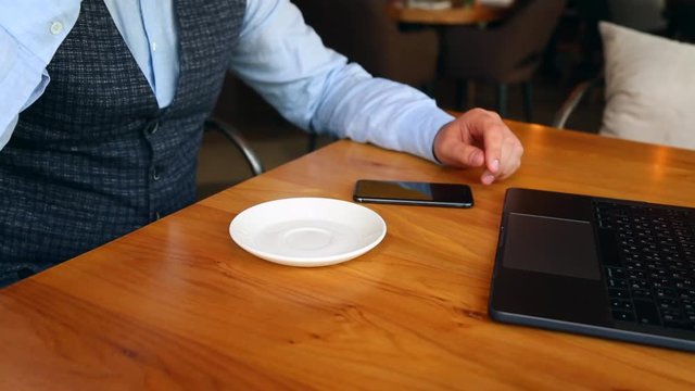 A young man uses smart phone and drink coffee while sitting at the bar
