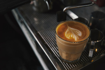 close-up view of glass cup with cappuccino and coffee machine