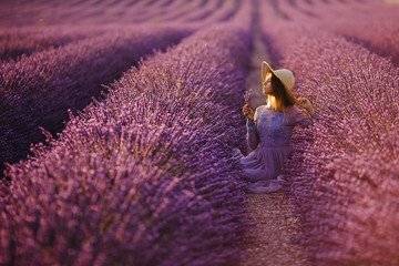 Woman in long and magnificent dress in purple fields of flowers lavender, France, Provence.