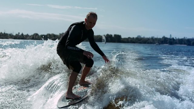 Wake surfing rider enjoy waves. Sportsman surfing on waves in slow motion. Water extreme lifestyle