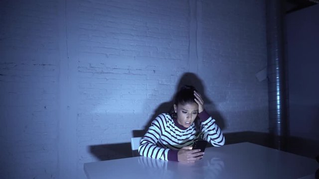 Frightened teenager or young woman using smart mobile cell phone as internet cyberbullying by message stalked abused victim.