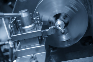 The  operation of lathe machine cutting the steel shaft in the light blue scene.