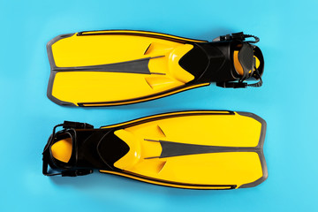 Pair of yellow flippers on color background, top view