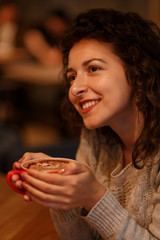 beautiful girl in gray knitted swether drinking coffee from cup in restraunt. close up portrait. Autumn mood