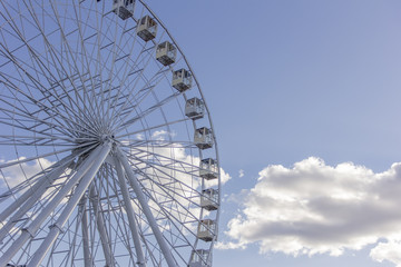 Obraz premium White fluffy clouds in deep blue sky, big Ferris wheel on sky background