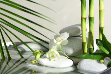 Spa stones, orchid and bamboo branches in water. Space for text - obrazy, fototapety, plakaty