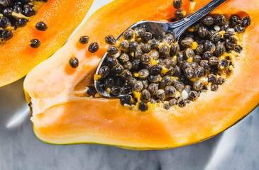Papaya fruit with seeds on white marble table.