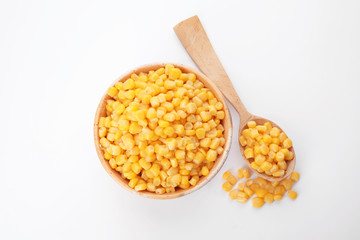 Bowl and spoon with corn kernels on white background, top view