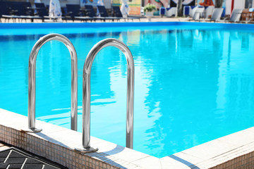 Modern swimming pool with step ladder outdoors