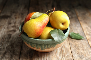 Bowl with ripe pears on wooden table