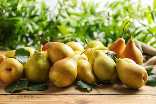 Ripe pears on wooden table against blurred background