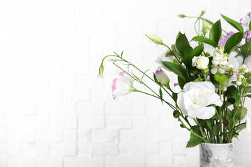 Vase with bouquet of beautiful flowers on blurred background. Space for text