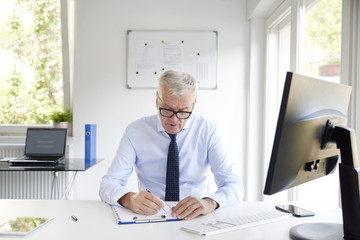 Thinking senior businessman writing something