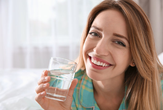 Young woman with glass of clean water at home