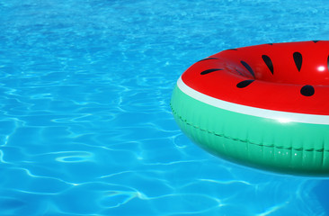 Fototapeta na wymiar Inflatable ring floating in swimming pool on sunny day. Space for text