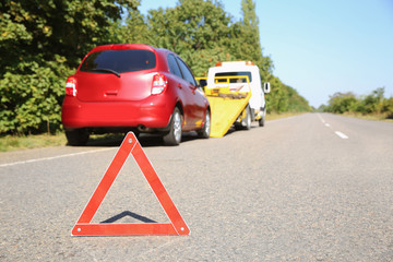 Emergency stop sign with broken car and tow truck on background. Space for text