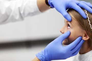 Child male optometrist examines eyesight of little girl