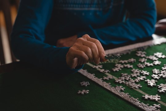 Senior woman playing jigsaw puzzle at home