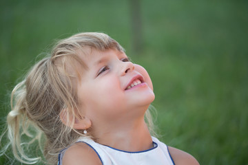 Kid with blond hair smile on green grass