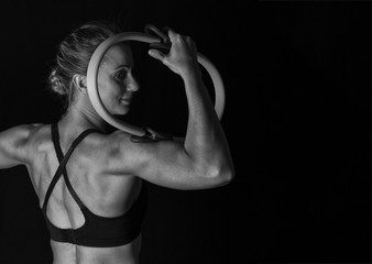 Fit woman with shaped muscles on her back and training hoop artistic conversion