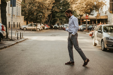 Careless man looking at mobile phone while crossing the street
