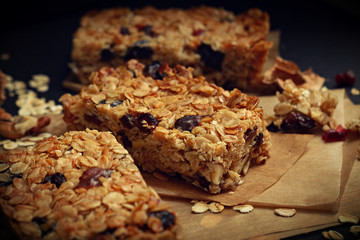 Homemade granola bars with nuts and cranberries over black background