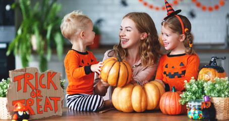 Fototapeta premium happy Halloween! family mother and children getting ready for holiday cutting pumpkin