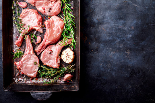 Meat Raw Fresh Mutton on the bone Spices Chesno and Rosemary on a black background pan Top View Copy space for Text