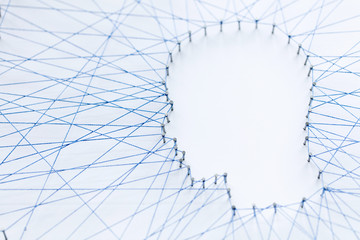 Human head shape made from a large grid of pins connected with string. Communication technology and...
