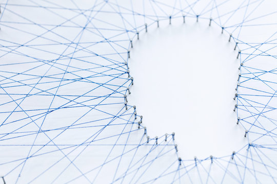 Human head shape made from a large grid of pins connected with string. Communication technology and mental health concept