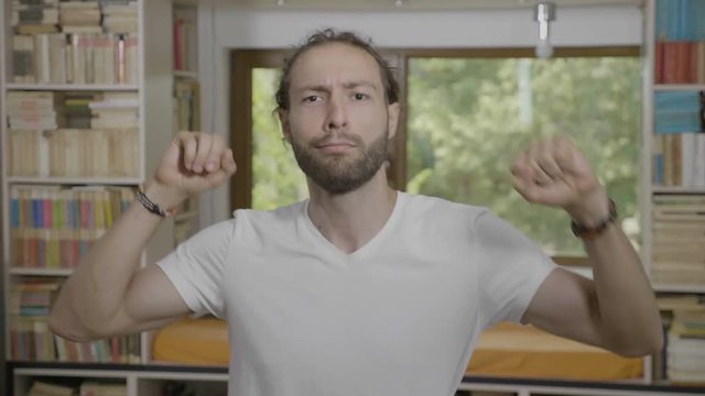 Amusing millennial bearded student man showing funny and silly dancing moves at library expressing joy and fun