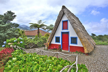 Fototapeta na wymiar Traditional home constructed with sloping triangular rooftops, and protected with straw, Santana, Madeira Island, Portugal