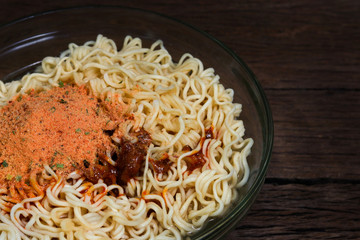 Instant noodles in bowl on wooden background.