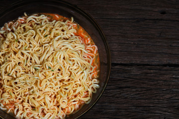 Instant noodles in bowl on wooden background.