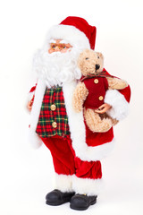 Santa Claus doll holding plush bear. Studio shot of plastic traditional greandfather frost holding cute brown teddy bear isolated on white background. Merry Christmas and happy New Year.