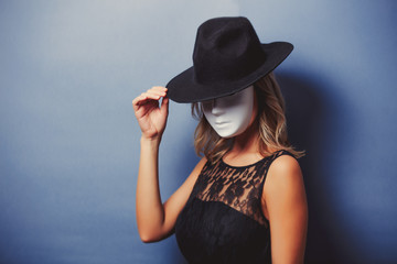 Portrait of a young style girl in black dress and white mask on gray background