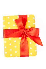 Yellow gift box with red bow. Box with present wrapped in yellow dotted paper with red satin ribbon isolated on white background.
