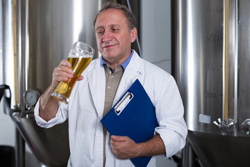 Adult expert is standing with folder and flask for beer and analizying it