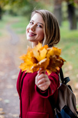 Young style girl with leaves in park alley in autumn season