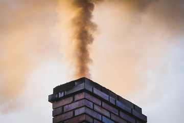 Thick smoke billowing out of a house chimney causing air pollution / smog